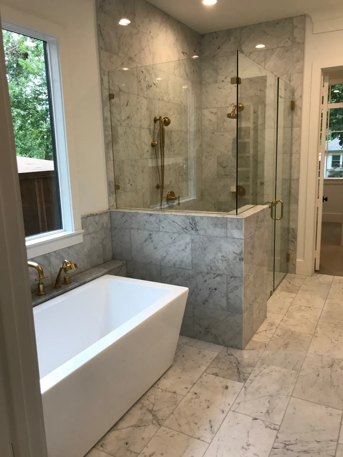 Carrara marble master bath with a freestanding tub and brushed-gold fixtures