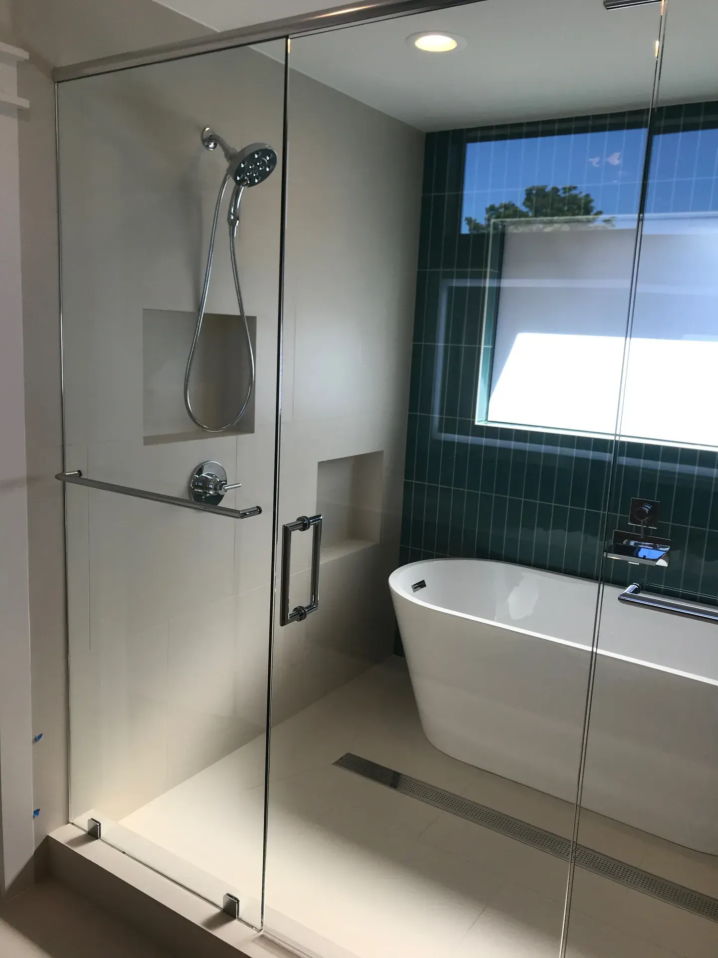 Master bath with a glass walk-in shower, freestanding tub, and green tile accent wall