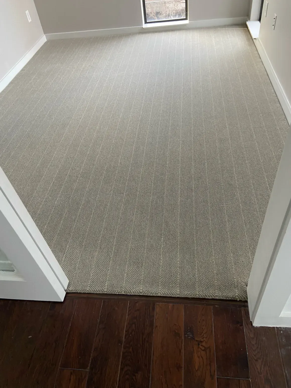 Gray striped carpet installed against a dark hardwood border