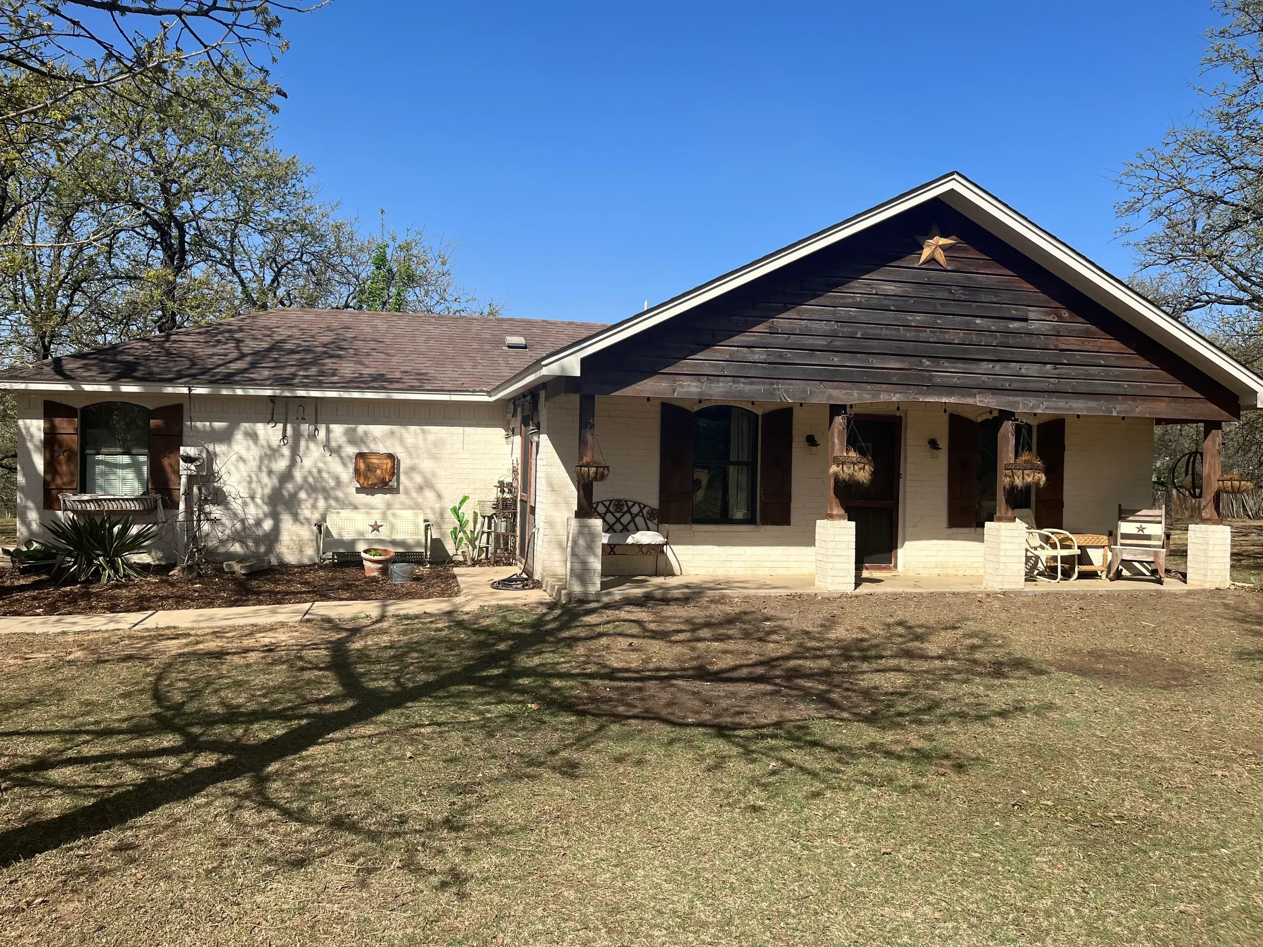 Rustic white-brick ranch home with a timber gable and Texas lone star