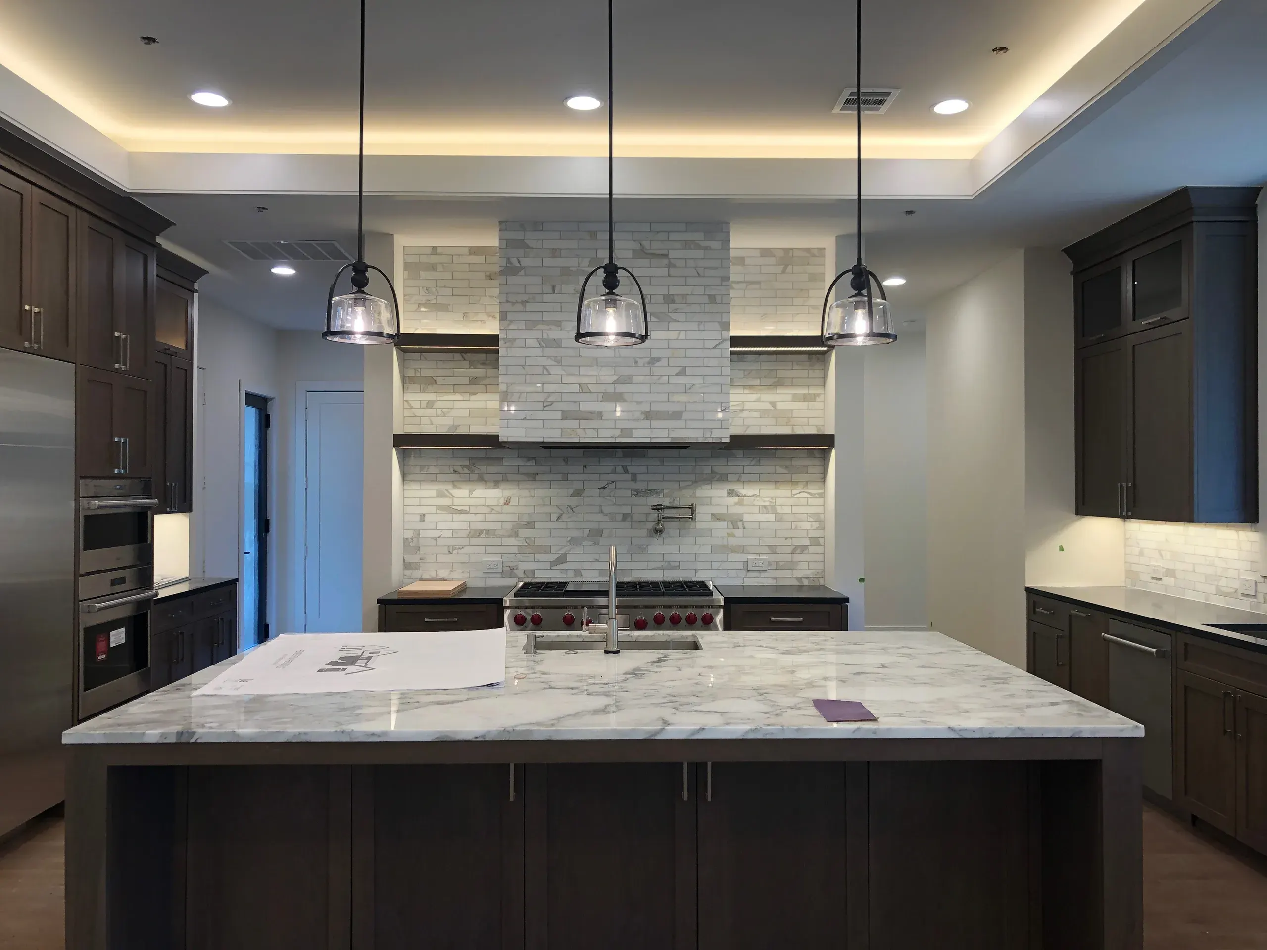 Custom kitchen with dark walnut cabinetry, a marble island, and pendant lighting