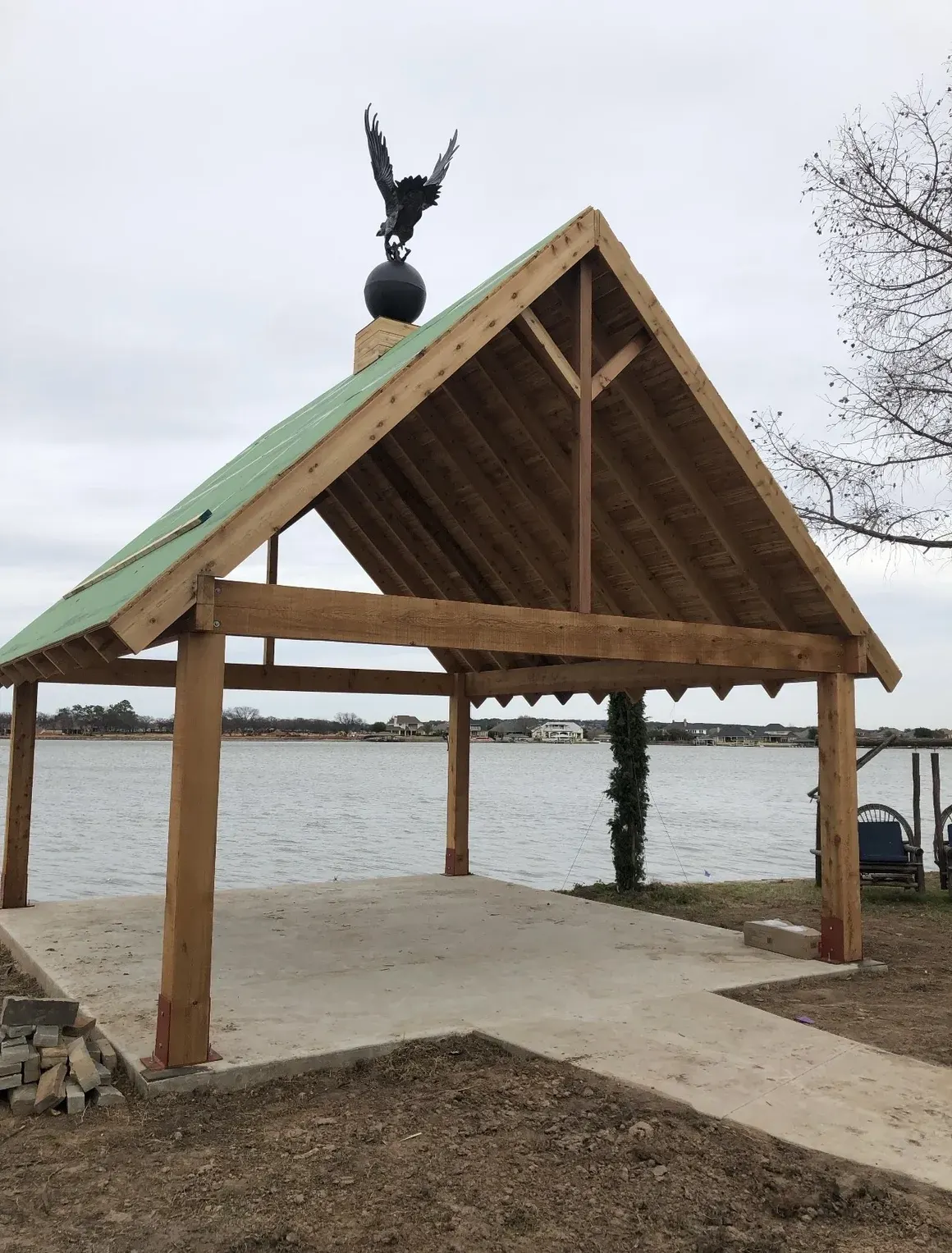 Cedar timber-frame lakefront pavilion topped with a bronze eagle finial