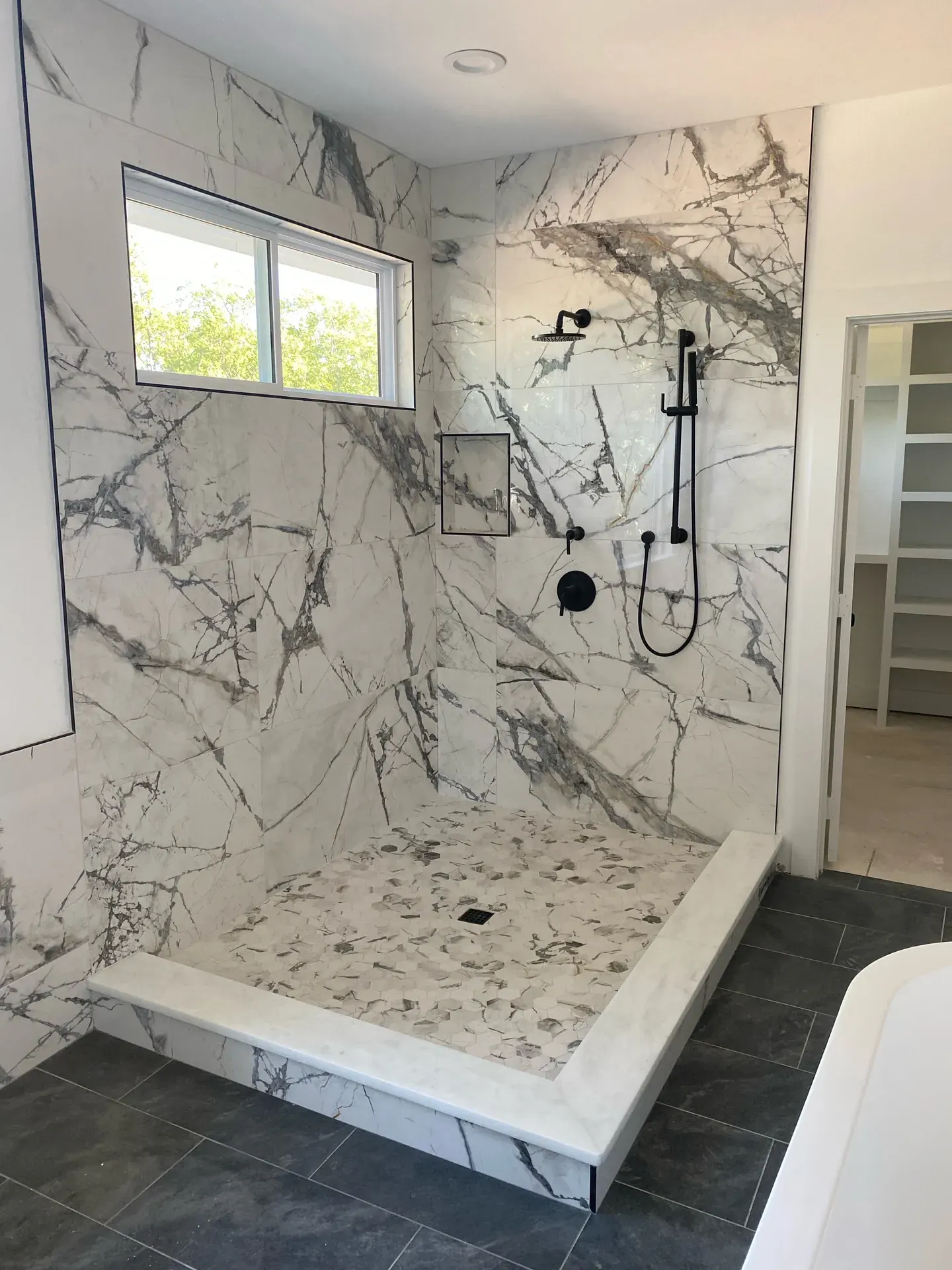 Book-matched marble walk-in shower with matte-black fixtures